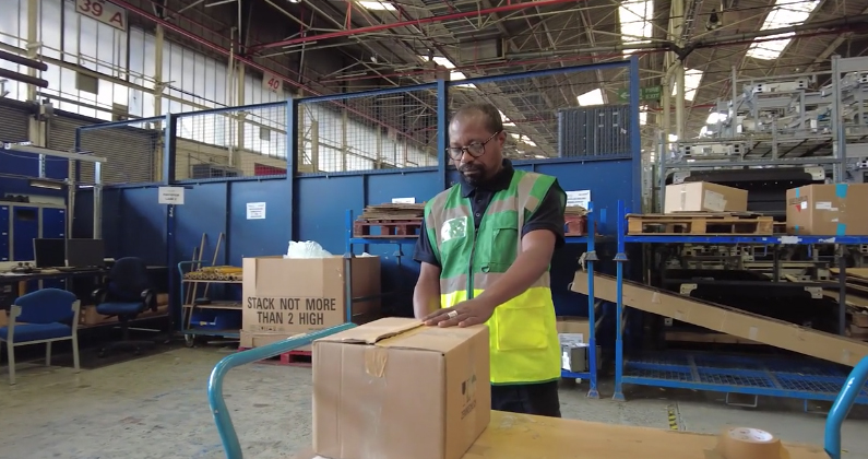 A Unipart employee recycling a box in a warehouse during Recycle Week