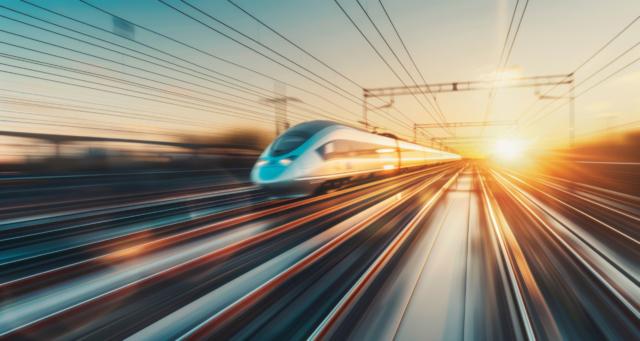 High-speed train blurring by, with motion blur signaling swift travel at dusk.