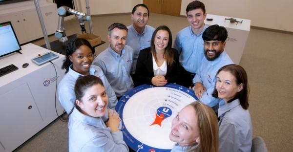 Unipart team members standing around a Unipart way board smiling.