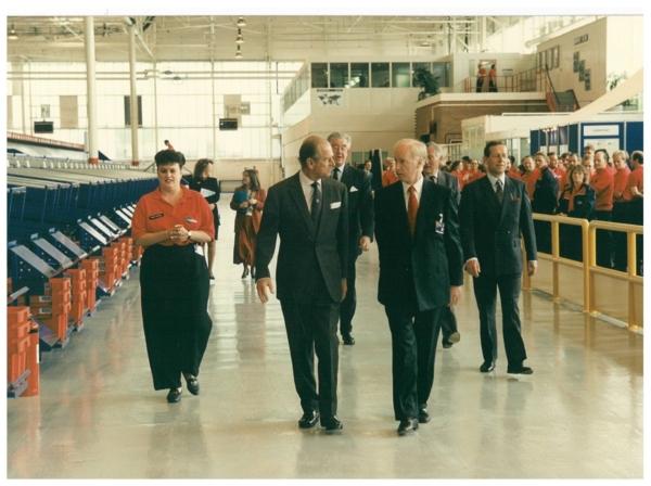 John Neill walking with Kind Phillip whilst giving a tour of a Unipart factory.