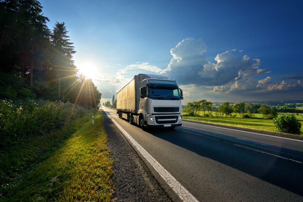 A logistics company truck driving through a rural area.