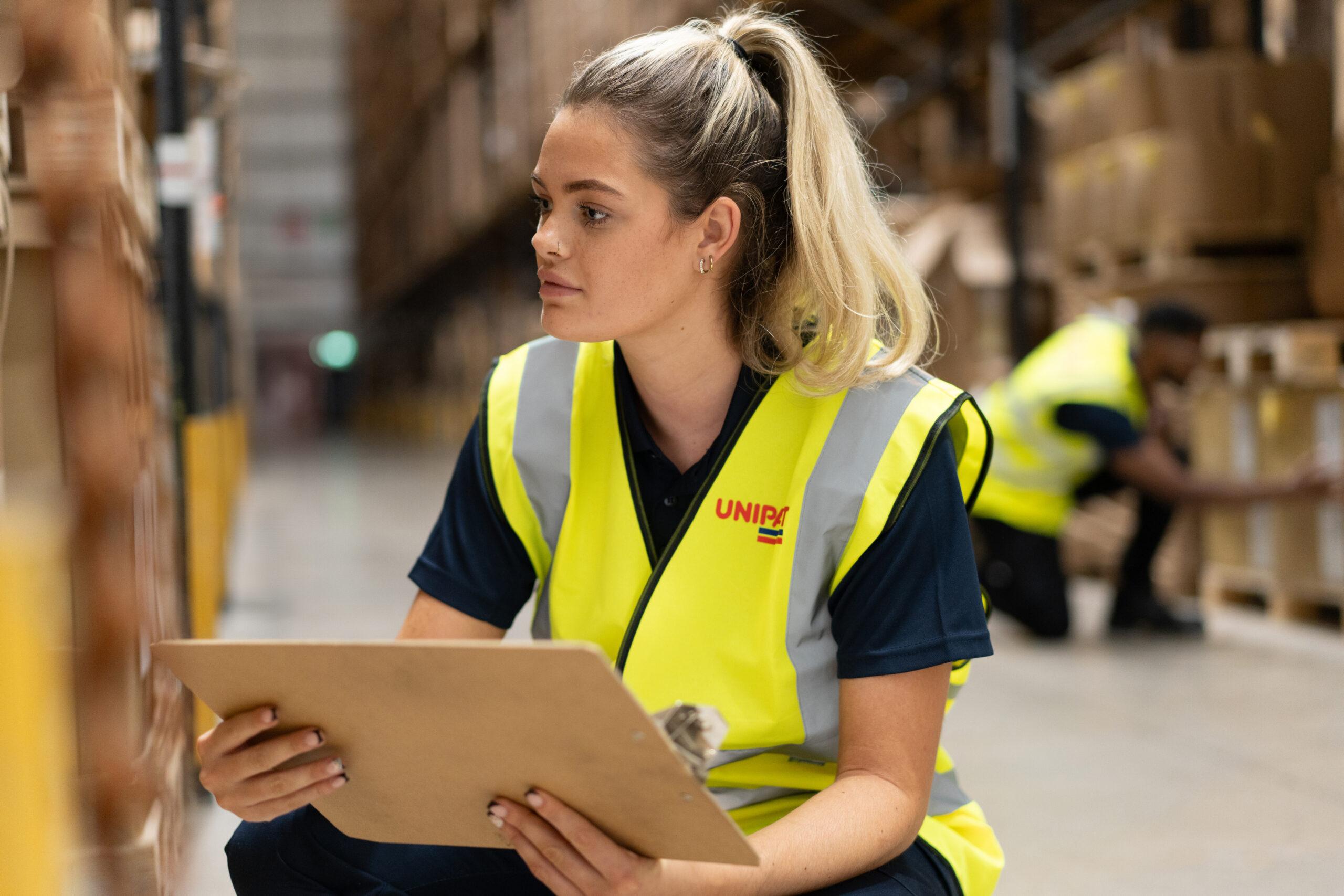 Unipart warehouse worker crouching inspecting inventory.