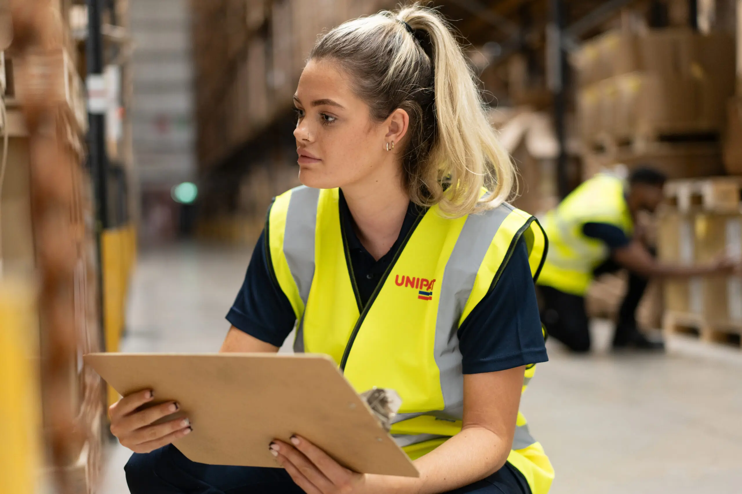 Unipart warehouse worker crouching inspecting inventory.