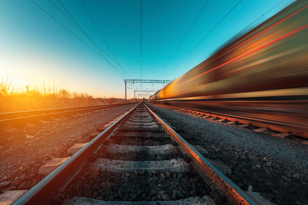 Blurred train in motion to one side with train tracks centre in sunset lighting.