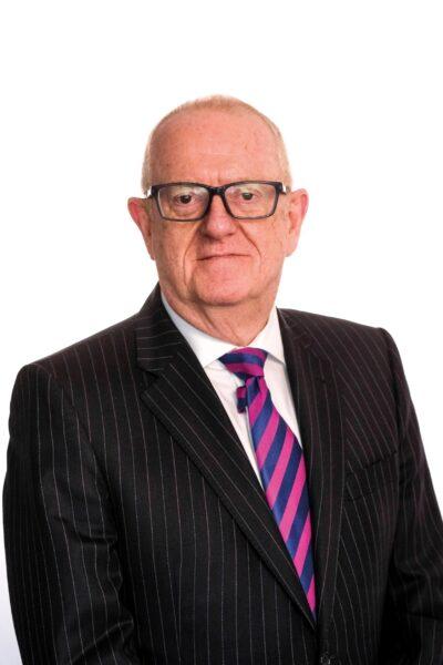Headshot of Bryan Jackson in black pinstripe suit and red and blue stripey tie.