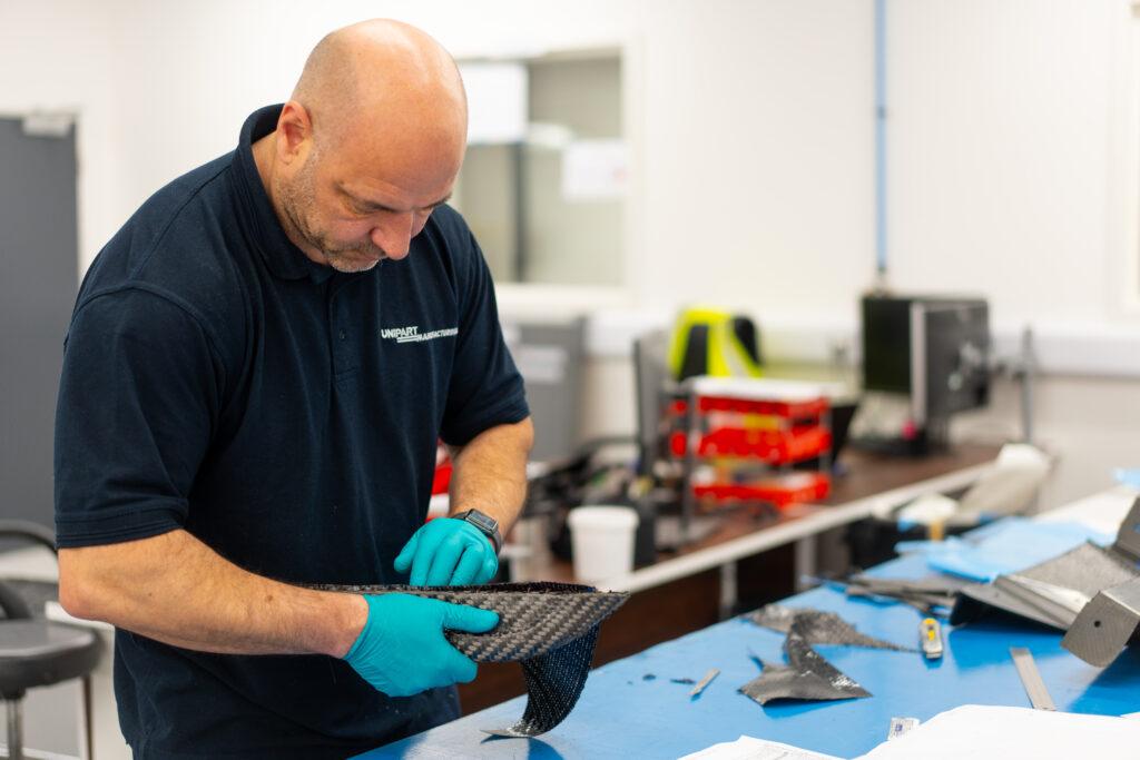 A man in the workshop inspecting a piece of material.