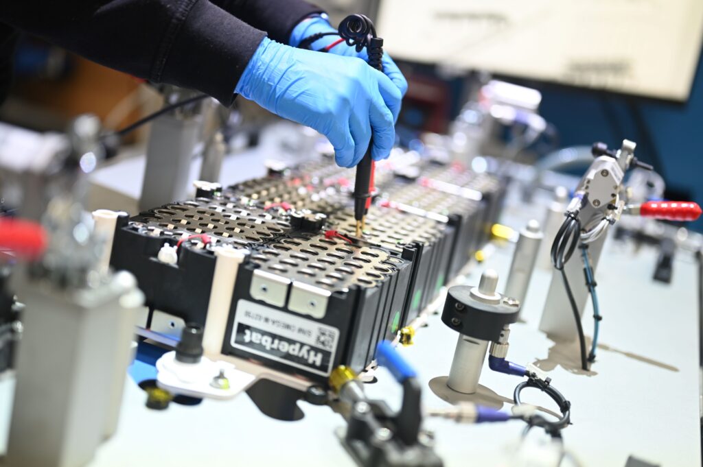 Engineer wearing blue gloves testing a battery module.