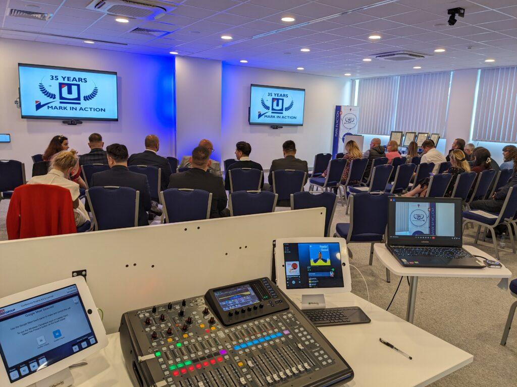 Unipart conference centre showing AV equipment behind an audience seated in chairs.