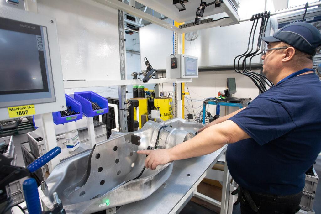 Man stood at workstation with a steel part in front of him.
